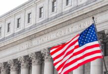 Frozen Iranian Cash Could Pay the Bill for Gulf War Damage American flag waves in front of a United States courthouse facade