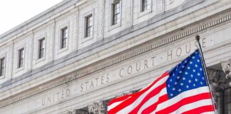 American flag waves in front of a United States courthouse facade
