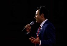 Viral Patriotism Message Sparks National Debate Man in a suit speaking into a microphone on stage