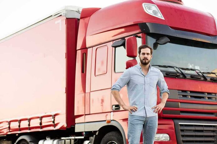 shutterstock_508483705 man standing in front of a red semi truck