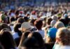 Extreme Heat Upends America 250 Celebrations Across the U.S. A large crowd of people gathered outdoors, with various hats and hairstyles visible
