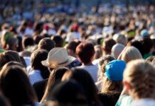 Extreme Heat Upends America 250 Celebrations Across the U.S. A large crowd of people gathered outdoors, with various hats and hairstyles visible