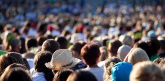 A large crowd of people gathered outdoors, with various hats and hairstyles visible