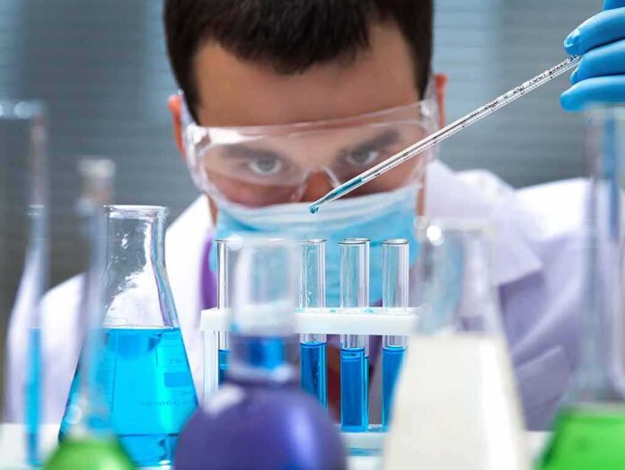 shutterstock_125266409 Scientist pipetting blue liquid into test tubes