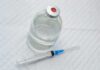 “Zombie Fat” Fillers Are the New Beauty Trend Vial of clear liquid with syringe on a white surface