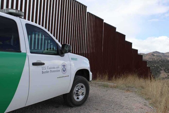 Border patrol SUV parked beside tall steel border fence