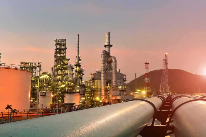 shutterstock_1569942199-1 Oil refinery with pipelines at sunset