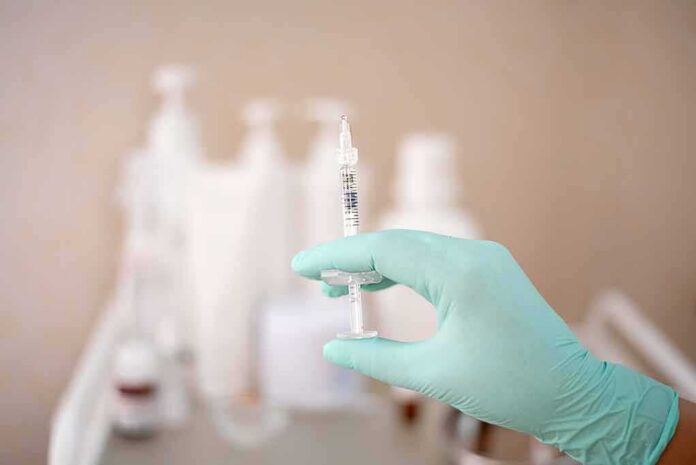 Gloved hand holding a syringe
