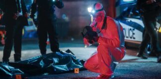forensic investigator photographs crime scene evidence at night
