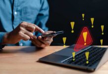 Person using smartphone near laptop with warning icons