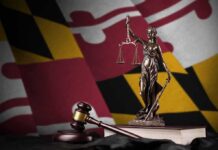 Maryland’s Big Tech Tax Collapses Lady Justice statue with gavel and book before a colorful flag backdrop