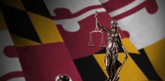 Maryland’s Big Tech Tax Collapses Lady Justice statue with gavel and book before a colorful flag backdrop