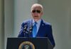 man in blue suit speaking at a podium with presidential seal