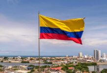 Colombian flag waving over a coastal city skyline