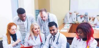 Medical students gathered around a laptop in a classroom