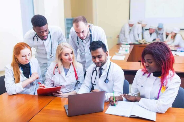 shutterstock_1034637484 Medical students gathered around a laptop in a classroom