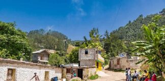 Rural village street with people gathered and hills in the background