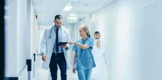 Four Patients Given Wrong Drug During Surgery Doctor and nurse walking in a hospital corridor reviewing a tablet