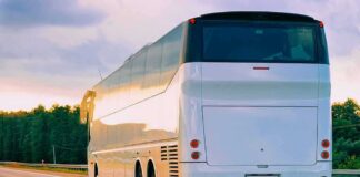 White coach bus driving on a highway at sunset