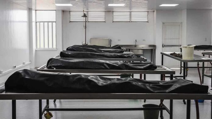 shutterstock_1442207993 Mortuary room with covered bodies on metal gurneys