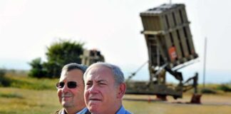 Ehud Barak and another man outdoors near a missile defense battery