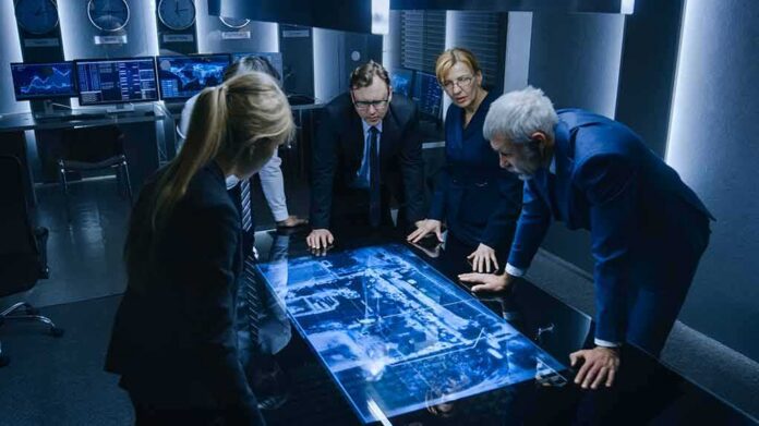 shutterstock_1506802679 Business team reviewing digital map on illuminated table