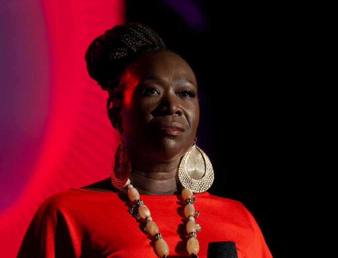 shutterstock_1518832127 Joy-Ann Reid on stage in dramatic lighting wearing a red outfit and large earrings