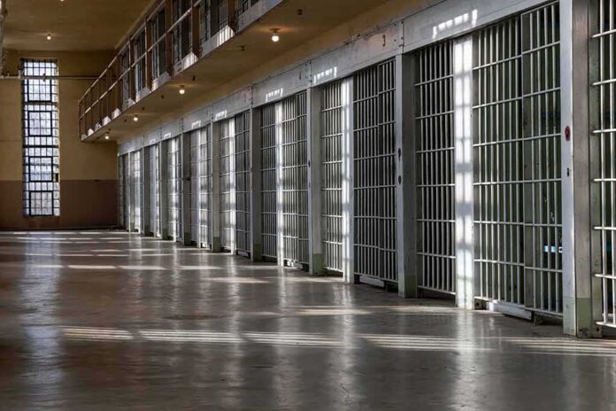 Row of prison cells with metal bars along an empty corridor