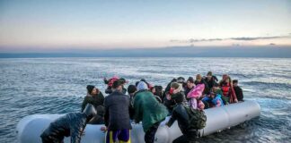 People arriving in a crowded inflatable boat at a rocky shore