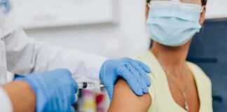 Healthcare worker gives vaccine injection to masked patient