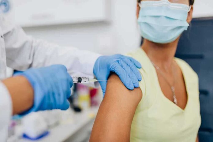 shutterstock_1789303814 Healthcare worker gives vaccine injection to masked patient