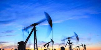 Oil pumpjacks operating at sunset over a reflective wet field