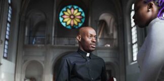 Bible Passage Fuels LGBTQ Interpretation Debate Priest speaking with a visitor inside a church