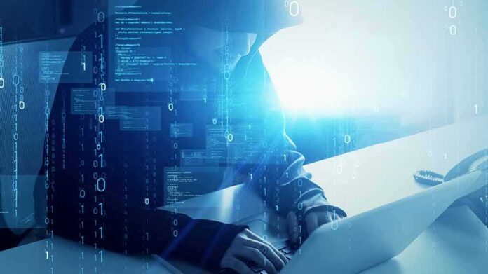 shutterstock_1984609274 Hooded figure using a laptop with digital code overlay
