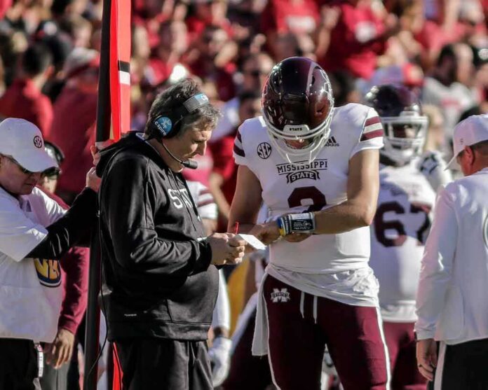 shutterstock_2070833297-2 Mississippi State football coach and quarterback review play card on sideline