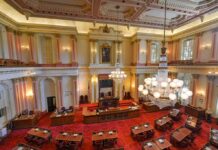 Congress Weaponizes Aid: Campuses On Notice Legislative chamber with red carpet and chandeliers