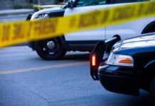 Gas Station Shooting Caught on Camera Police cars behind yellow caution tape at a street scene
