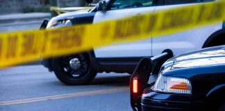 Gas Station Shooting Caught on Camera Police cars behind yellow caution tape at a street scene