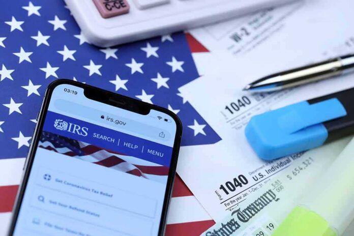 shutterstock_2115308666 Smartphone showing IRS website on top of tax forms and office supplies