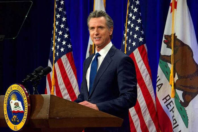 Man in suit speaking at a podium with American and California flags