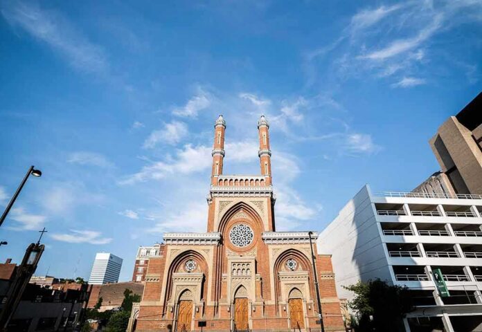 shutterstock_2184079581 historic brick church with twin towers against blue sky