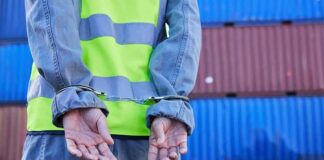 Worker in safety vest handcuffed at a shipping yard