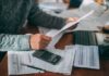 Burisma Board Income Linked to Active Crack Cocaine Addiction Person reviewing bills with calculator at cluttered desk