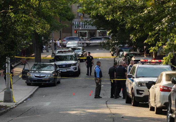 shutterstock_2330301305-4 Police officers secure a residential street with patrol cars and yellow tape