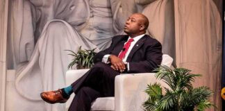 Tim Scott seated on a white armchair on stage