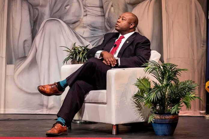 Tim Scott seated on a white armchair on stage