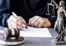 Mistrial Declared After Juror Dispute in Murder Case Judge writing at desk with gavel and Lady Justice statue