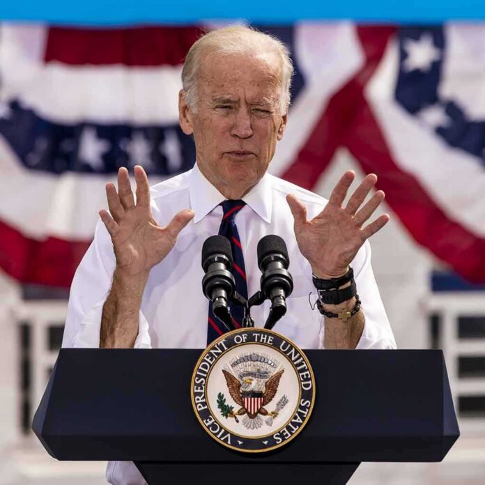 shutterstock_638168158 Joe Biden speaking at a podium with microphones and patriotic bunting