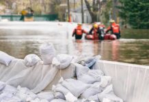 Nor’easter Floods New Jersey Shore Sandbags stacked near a flooded street with rescue workers in a boat