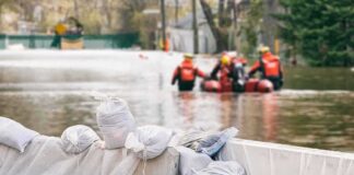 Nor’easter Floods New Jersey Shore Sandbags stacked near a flooded street with rescue workers in a boat